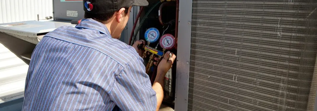 HVAC technician servicing a condenser unit in Vineyard